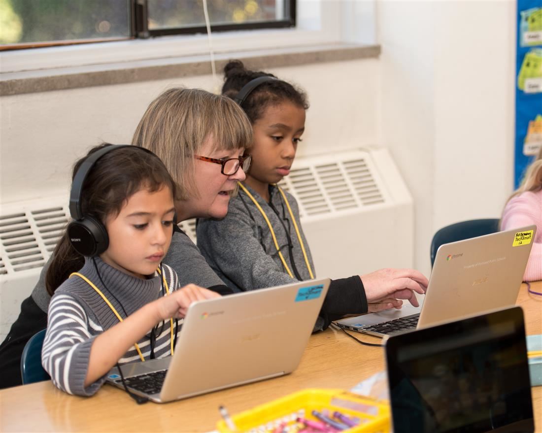 Students with teacher working on laptop